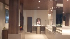 A modern interior with a central counter, wooden columns, and a staircase. - Hotel Sai Palace Express (Rahata)