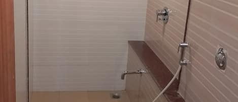 A bathroom with a toilet, a shower, and a window with a patterned glass door.