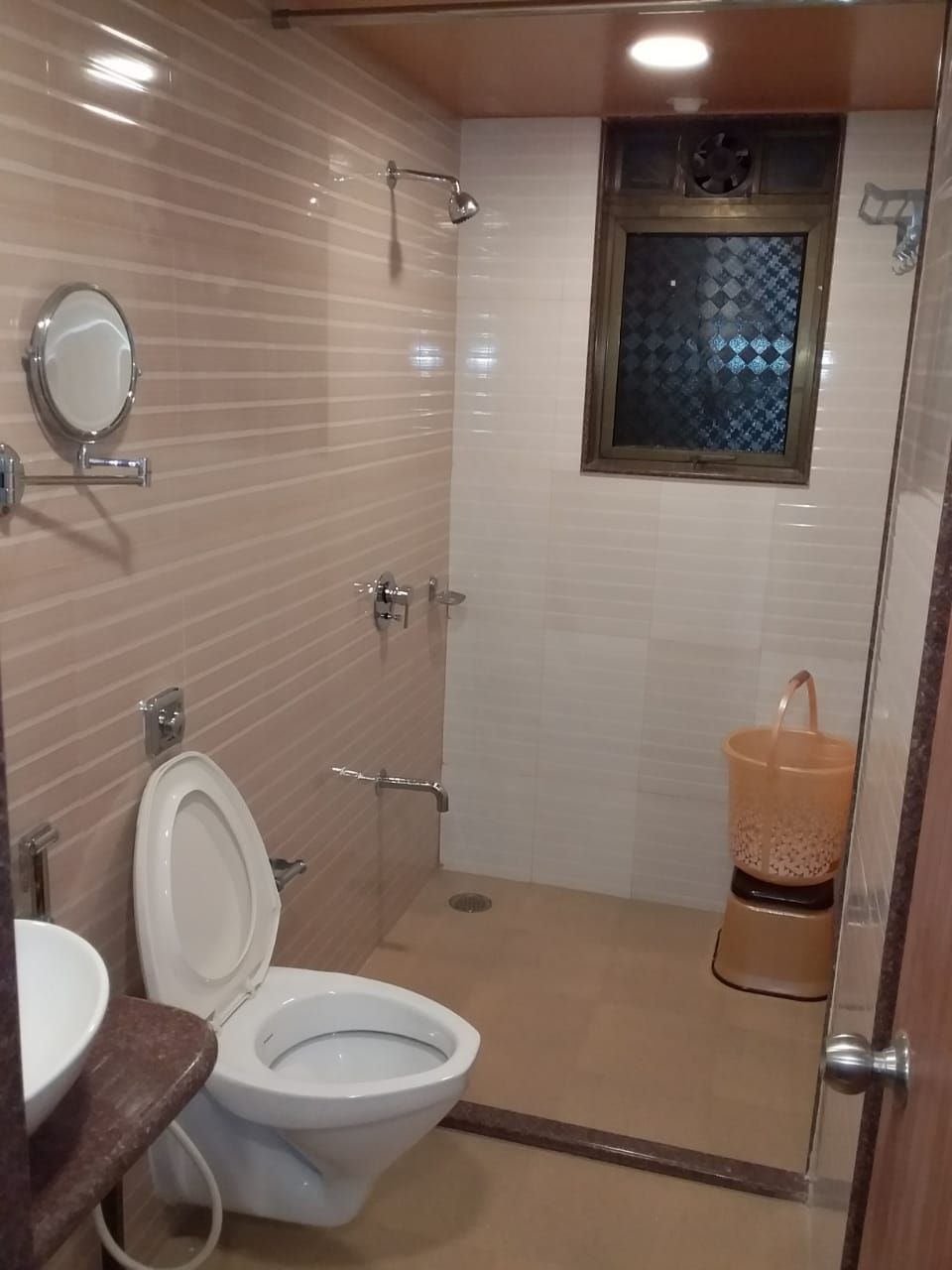 A bathroom with a toilet, a sink, a shower, and a window.