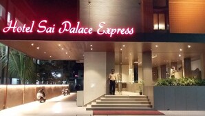 The exterior of Hotel Sai Palace Express with a modern design, featuring a prominent neon sign, a staircase leading to the entrance, and a well-lit facade. - Hotel Sai Palace Express (Rahata)