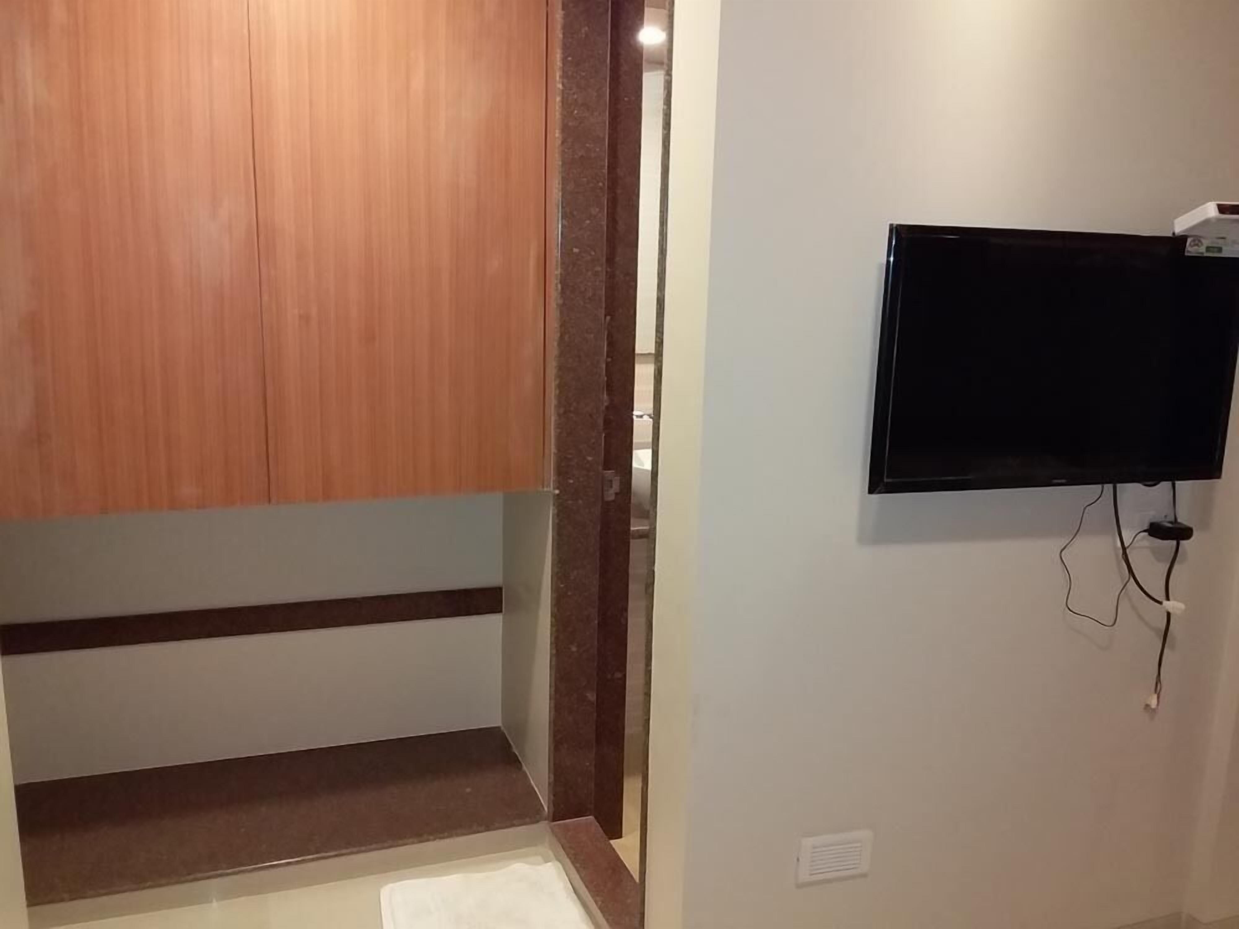 Una habitación con un armario de madera, un televisor de pantalla plana en la pared y suelo de baldosas.