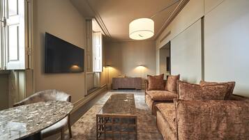 Een moderne woonkamer met een bank, een salontafel en een aan de muur bevestigde televisie.