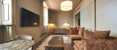 A modern living room with a sofa, a coffee table, and a TV mounted on the wall.