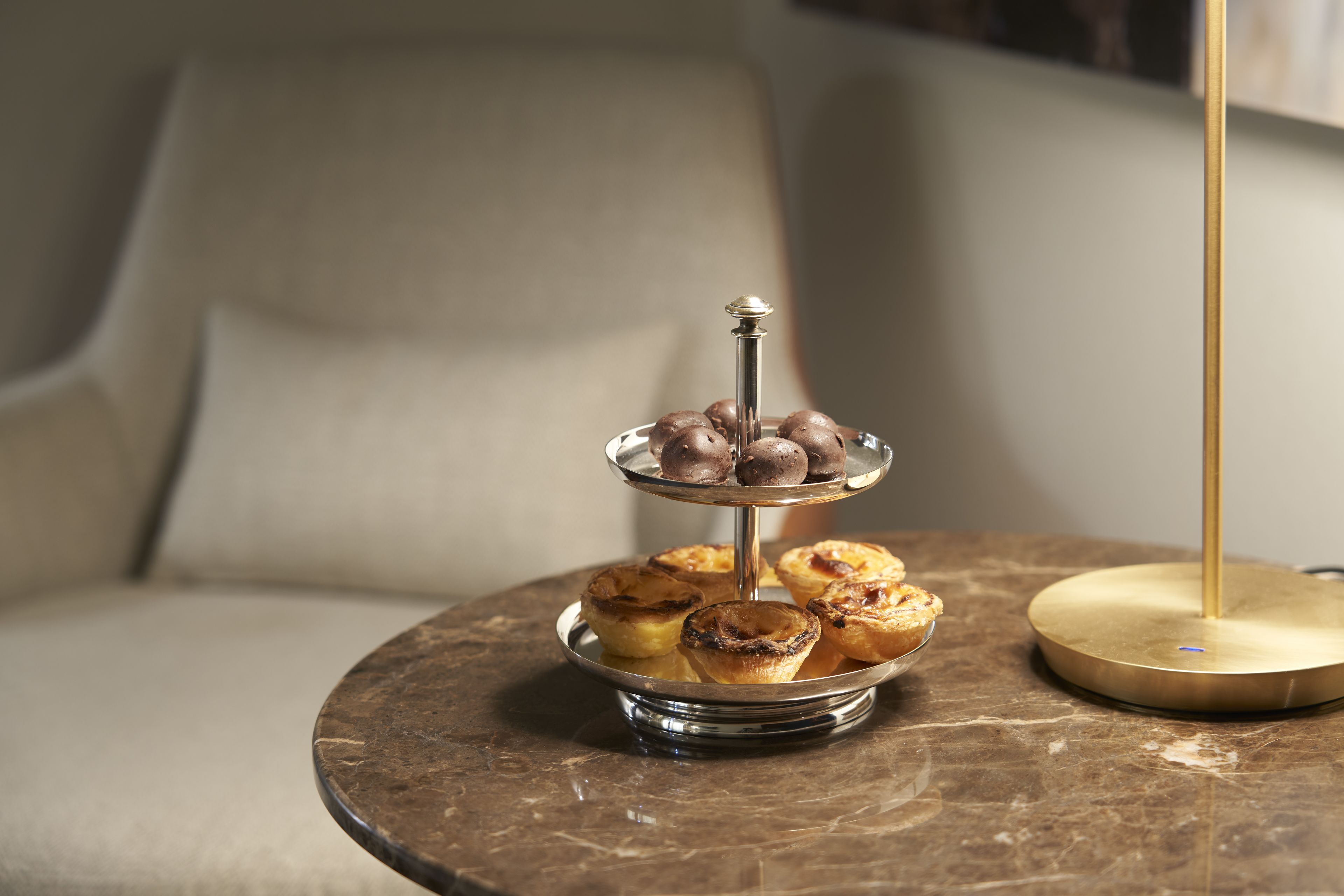 A round marble table with a tiered stand holding pastries.