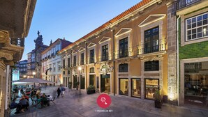 Un bâtiment historique doté d’une terrasse extérieure couverte et de boutiques au rez-de-chaussée.