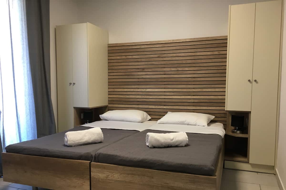 Habitación de hotel moderna con cama de madera, cabecero blanco y armario empotrado.