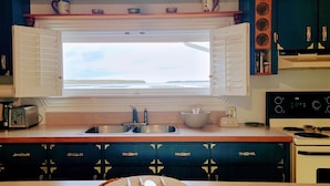 A kitchen with a large window, a stove, a sink, and a toaster. - The Dream chalet  (Cocagne)