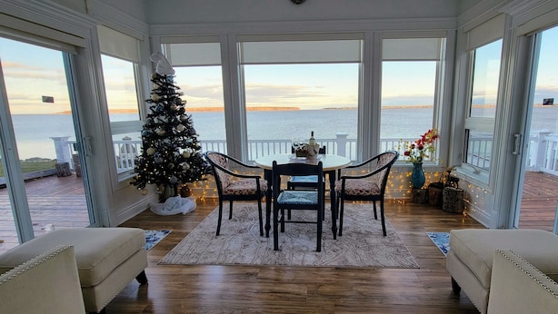 A conservatory with a Christmas tree, a dining table with chairs, and a view of the sea. - The Dream chalet  (Cocagne)