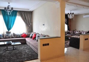 A living room with a sectional sofa, a coffee table, and a chandelier.