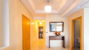 Un couloir avec une porte en bois, une console surmontée d’un vase et un miroir accroché au mur.