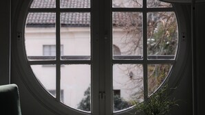 A room with a large circular window, a potted plant on the windowsill, and a chair. - Oasi di Cavoretto 97 - Casa per Ferie (Turin)