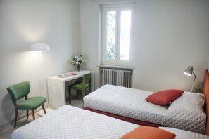 A bedroom with two beds, a desk, a chair, a radiator, and a window. - Oasi di Cavoretto 97 - Casa per Ferie (Turin)