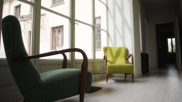 Ein Zimmer mit einem großen Fenster, einem grünen Sessel und einem gelben Stuhl.