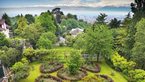 A landscaped garden with circular flower beds and a bench. - Oasi di Cavoretto 97 - Casa per Ferie (Turin)