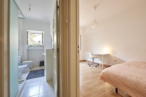 Relax in a spacious room with a large bed, desk, and chair, offering a comfortable space for work or rest.