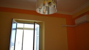A room with an open window, a ceiling-mounted air conditioning unit, and a hanging lamp with a striped pattern. - L'Aquilone B&B (Palermo)