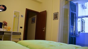 A room with a bed, a desk, a chair, a mirror, and a door leading to another room. - L'Aquilone B&B (Palermo)