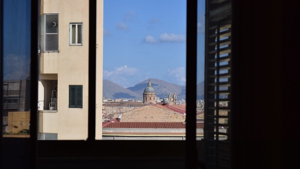 A view through a window of a building with a large dome and mountains in the background. - L'Aquilone B&B (Palermo)