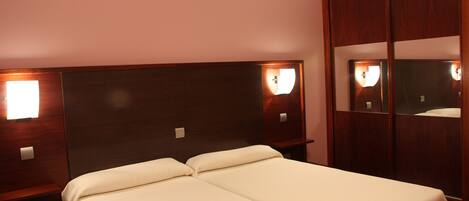 A hotel room with a double bed, wooden headboard, and a mirror cabinet.