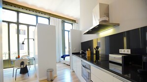 A modern kitchen with a black countertop, white cabinets, and a stainless steel range hood.
