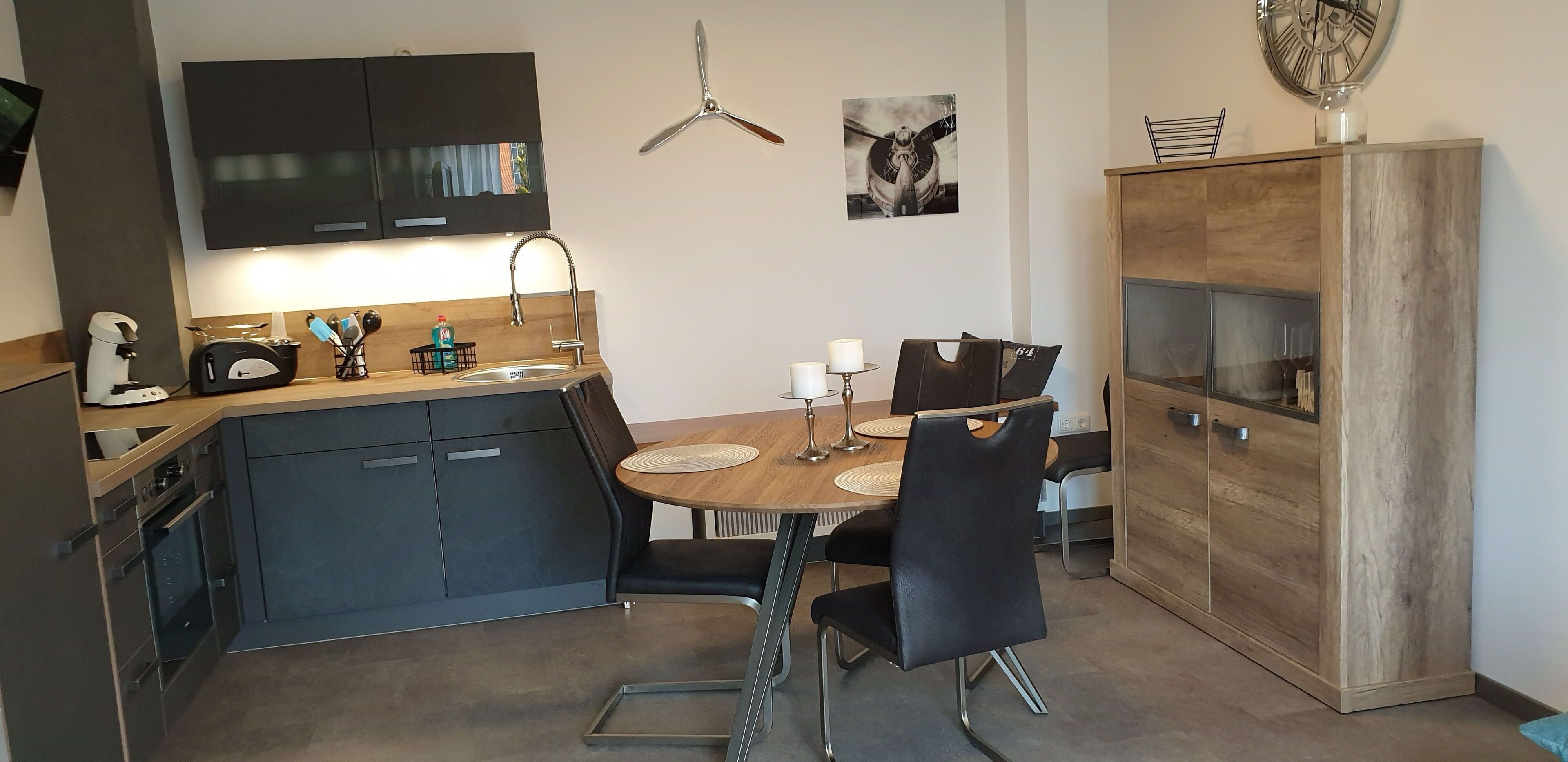 Una cocina moderna con armarios oscuros, una mesa de comedor de madera y sillas negras.