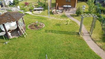 A well-maintained garden with a wooden cabin, a small patio area, and a paved walkway.