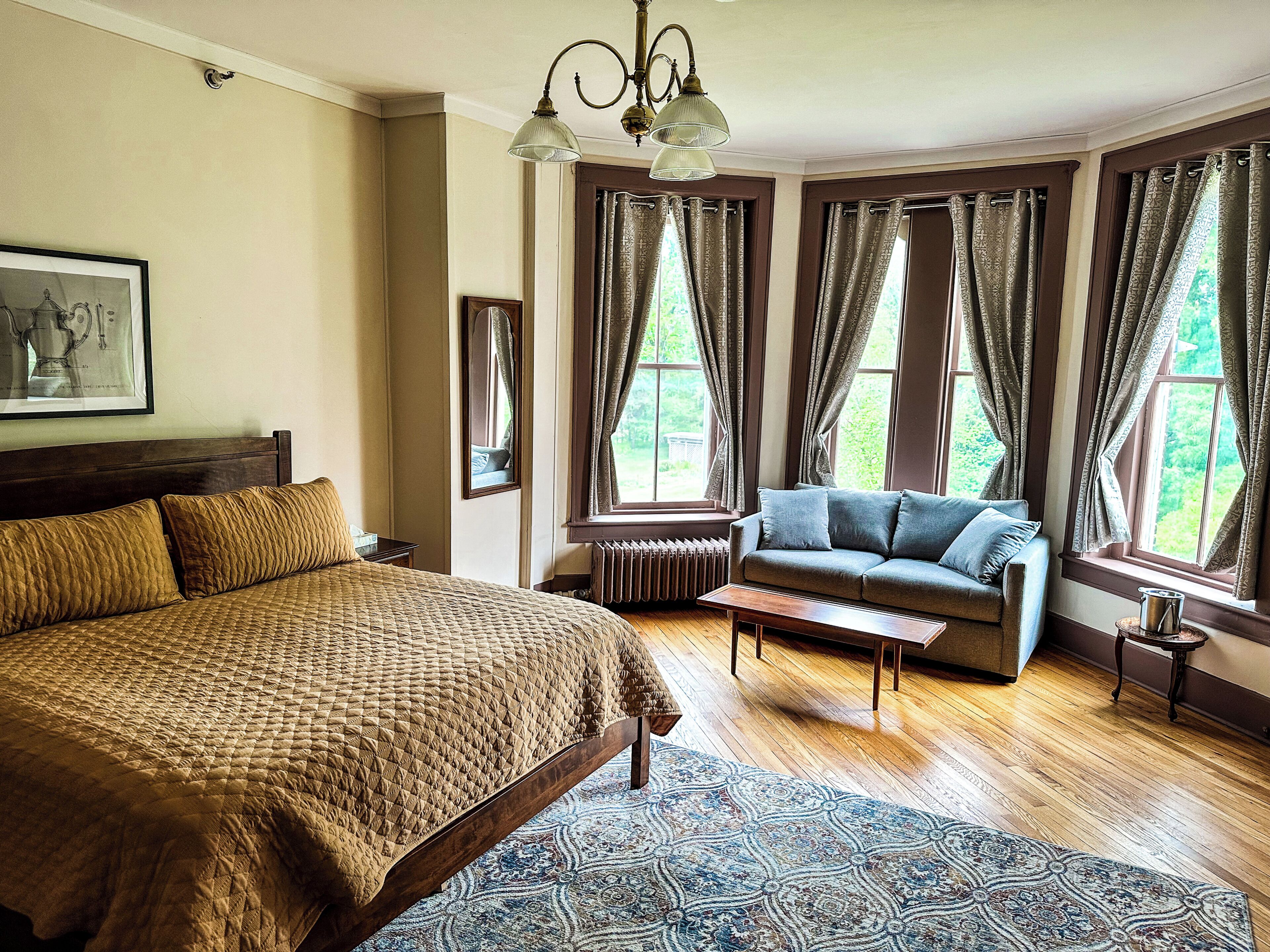 A room with a large bed, a sofa, a small table, and a radiator.