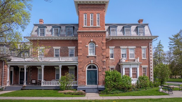 A large, historic brick building with a central tower, multiple windows, and a covered porch. - Oneida Community Mansion House (Oneida)