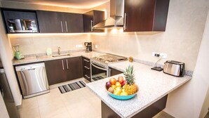 A modern kitchen with dark cabinets, a stainless steel dishwasher, a built-in oven, a microwave, and a toaster. - WINTER OFFER!! CHIC & MODERN BEACHFRONT CONDO W/TERRACE (Puerto Vallarta)