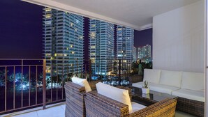 A balcony with wicker furniture and a white sofa, overlooking a cityscape at night. - WINTER OFFER!! CHIC & MODERN BEACHFRONT CONDO W/TERRACE (Puerto Vallarta)