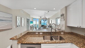 A kitchen with granite countertops, a stainless steel sink, and a ceiling fan.