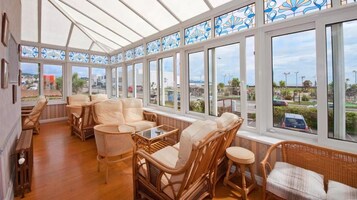 Un salón con ventanales, muebles de mimbre y vistas al exterior.