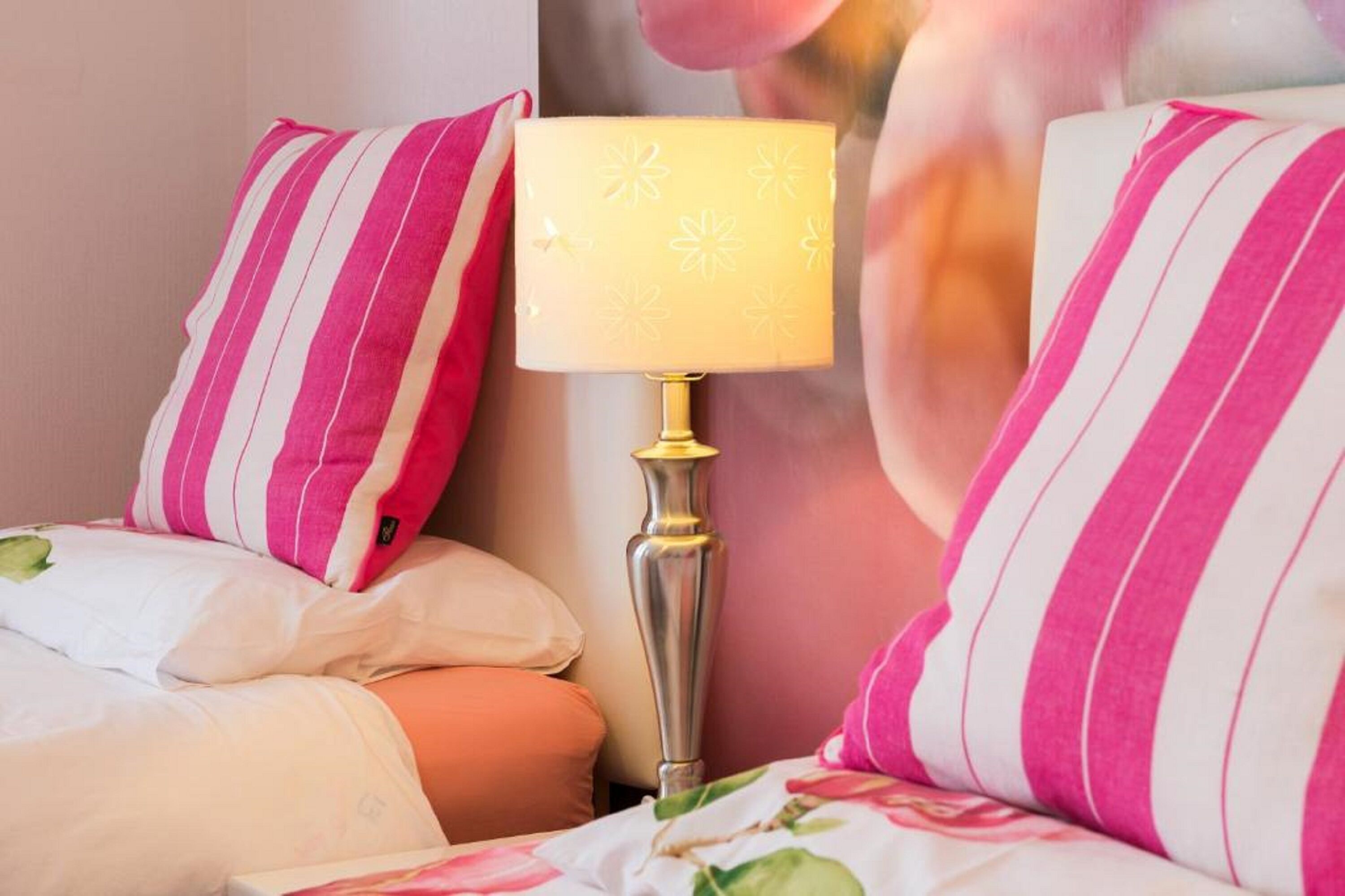 Una cama con almohadas a rayas y una lámpara con estampado floral.