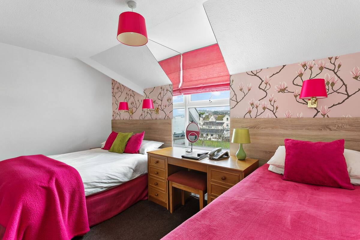 Ein Schlafzimmer mit zwei Betten, einem Schreibtisch und einem Fenster mit Blick.