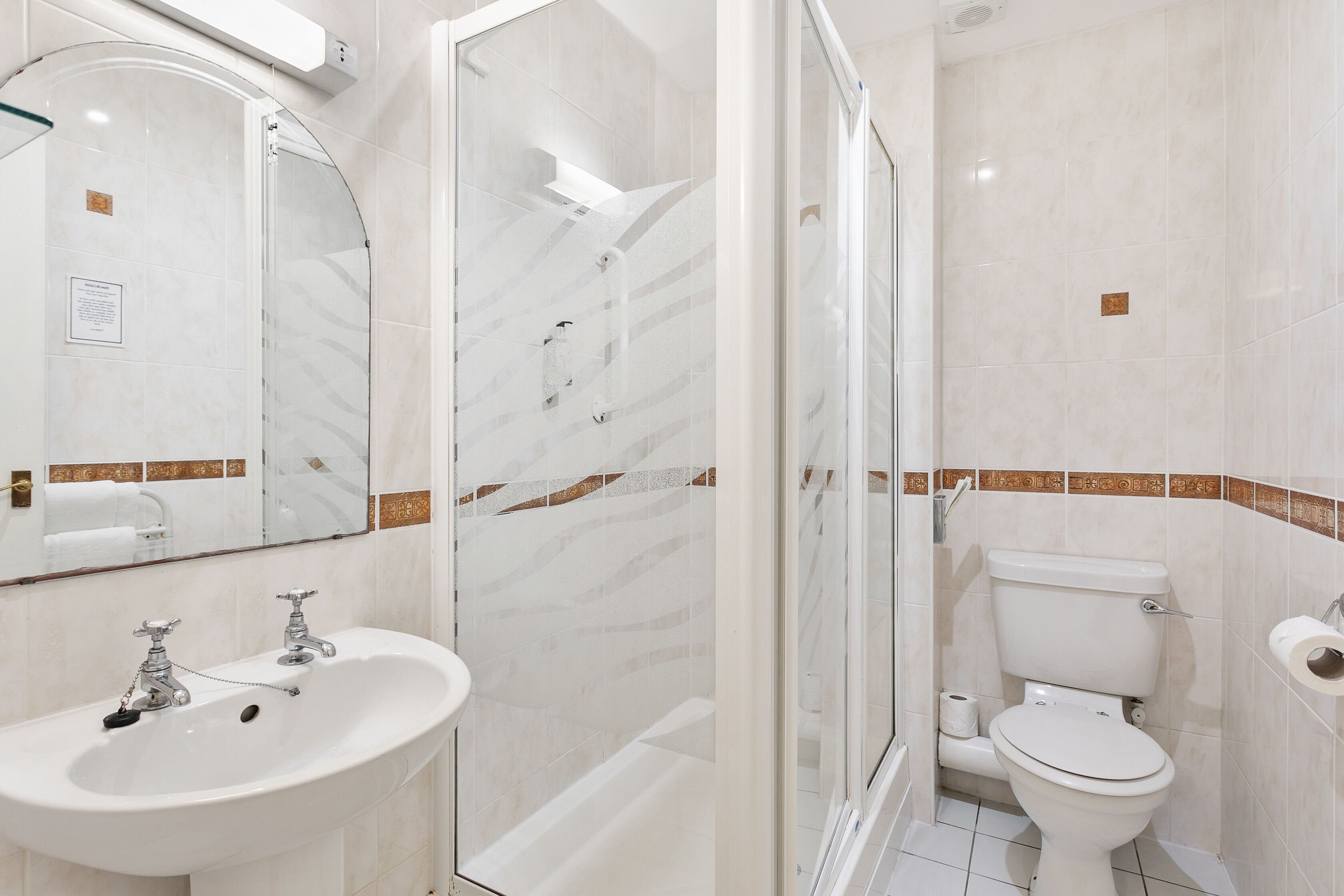 A bathroom with a glass-enclosed shower, a sink, and a toilet.