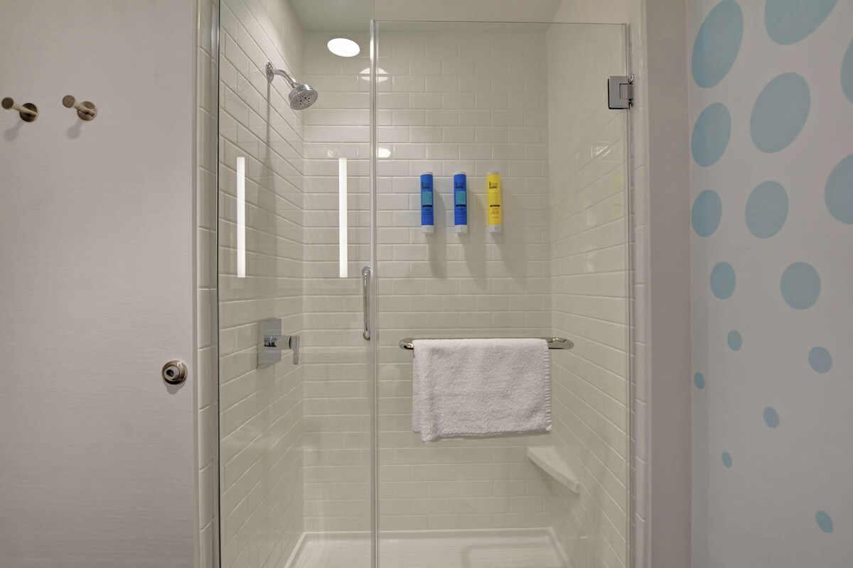 A modern bathroom with a glass shower enclosure, white tiled walls, and a white towel hanging on a rack.