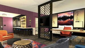 Una habitación de hotel moderna con una zona de bar, una cama grande, un sofá y un panel decorativo en la pared.