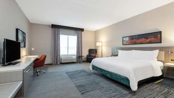 A hotel room with a bed, desk, chair, and a television.
