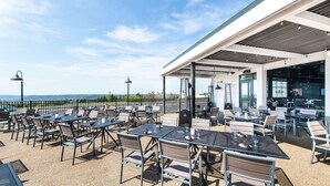 Un patio al aire libre con mesas y sillas, con vista a una masa de agua.