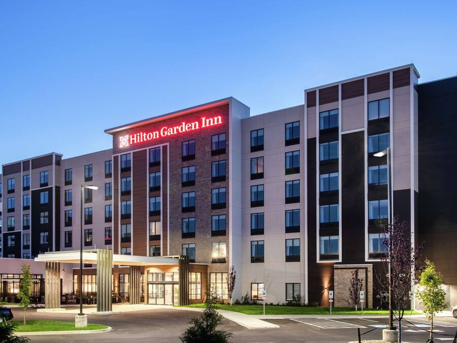 Un Hilton Garden Inn con fachada moderna, varios pisos y una entrada bien iluminada.