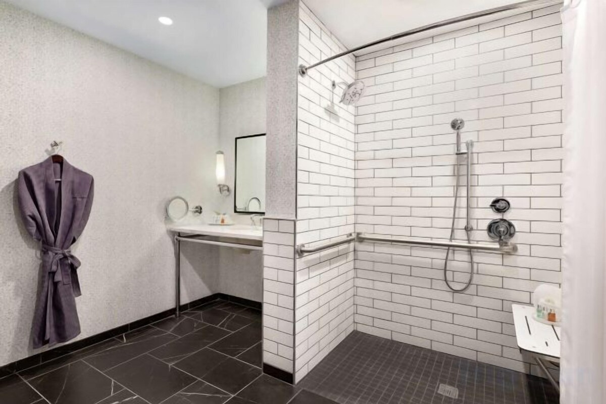 A modern bathroom with a shower, a sink, and a robe hanging on the wall.