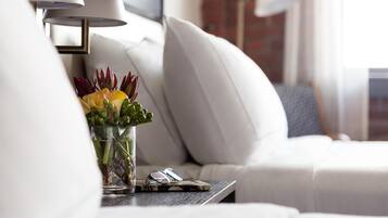 A modern living room with a sofa, a glass vase with flowers, a lamp, and a book.