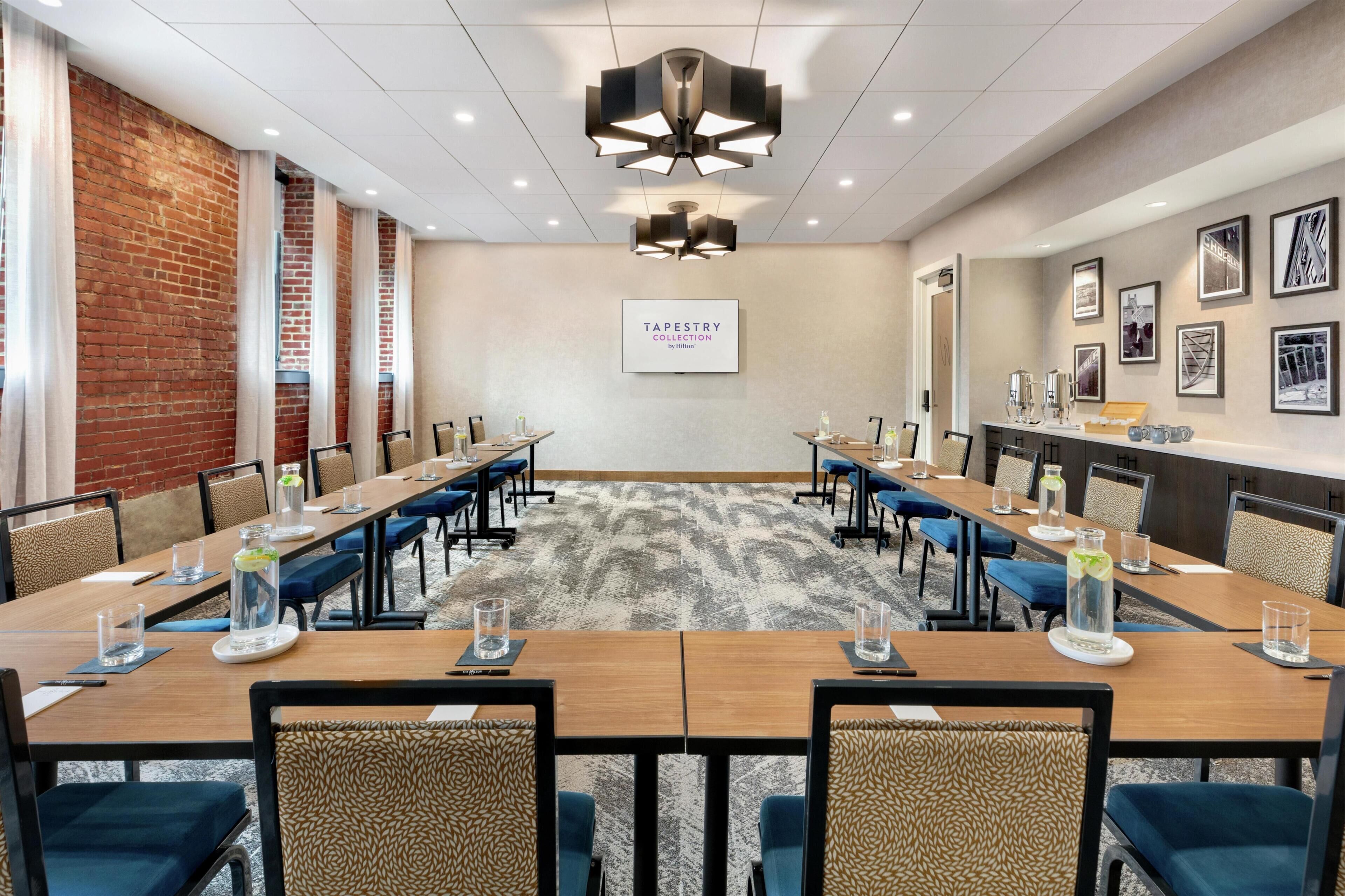 A conference room with a long table, chairs, a carpeted floor, and a 'TAPESTRY COLLECTION' sign on the wall.