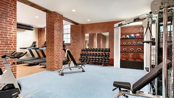 A gym with treadmills, a bench press, and a wall of dumbbells.
