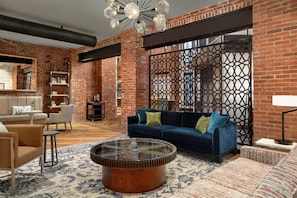 A living room with a blue sofa, a round coffee table, and a patterned rug. - The Wilbur Lititz, Tapestry Collection by Hilton (Lititz)