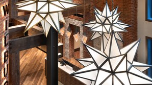 A hotel interior with a reception desk, wooden flooring, and hanging star-shaped light fixtures. - The Wilbur Lititz, Tapestry Collection by Hilton (Lititz)