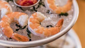 A plate of shrimp on ice with a small bowl of sauce.