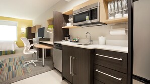 A modern kitchen with dark wood cabinets, stainless steel appliances, and a white countertop. - Home2 Suites by Hilton Houston-Pearland (Houston)