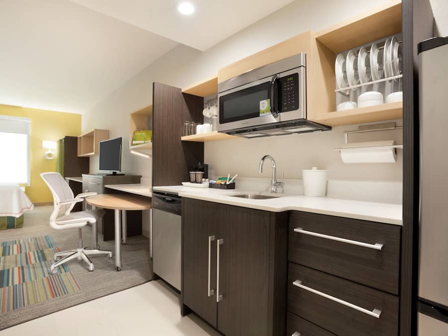 A modern kitchen with dark wood cabinets, stainless steel appliances, and a white countertop.