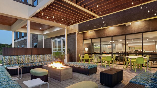 An outdoor seating area with fire pits, green chairs, and a modern design. - Home2 Suites by Hilton Houston-Pearland (Houston)